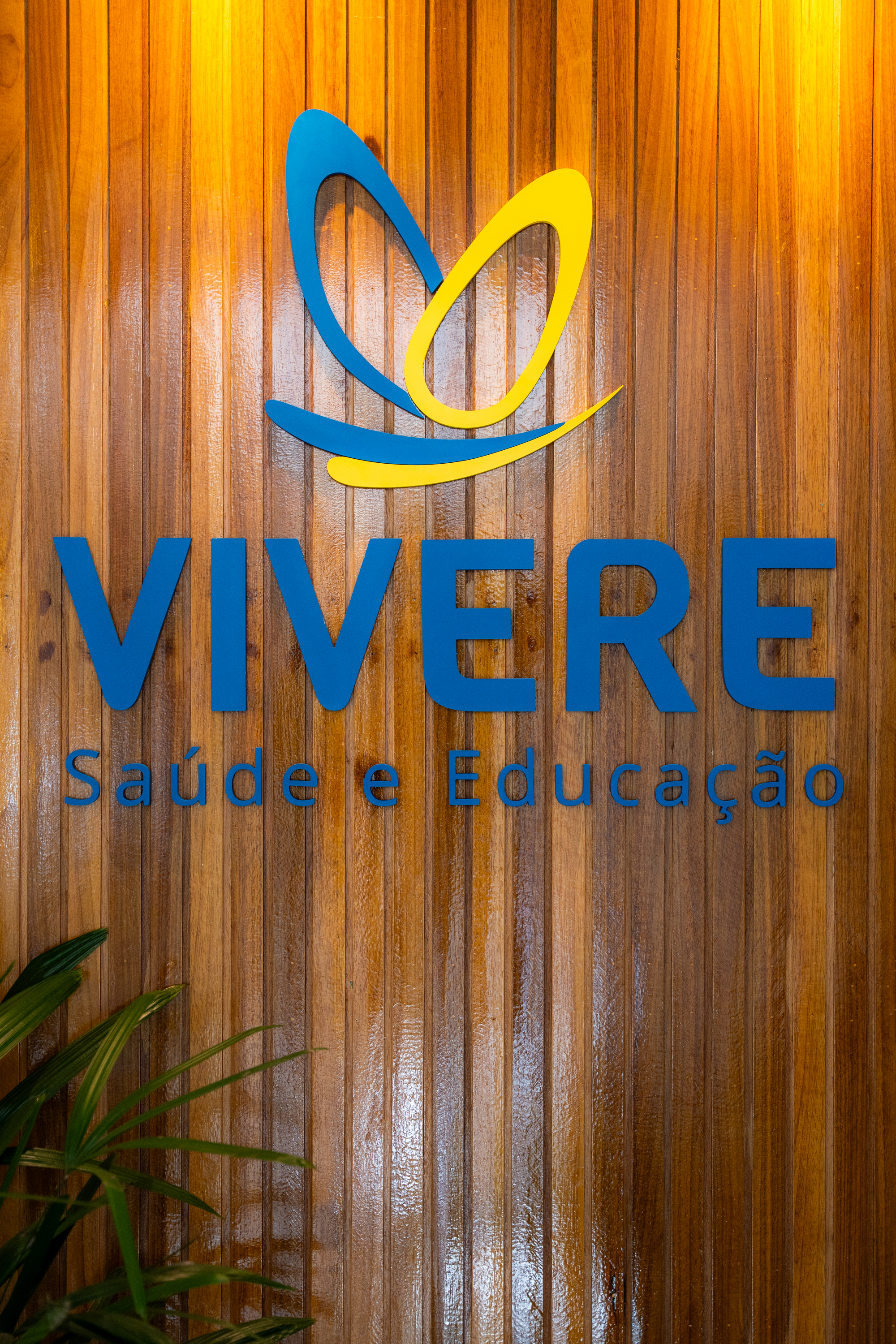 Fachada interna da Vivere Saúde com logo em painel de madeira